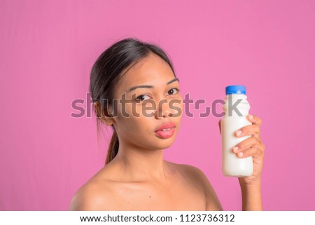 Healthy young asian latin woman with bottle of milk. Female different emotions on over a pink background.