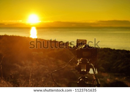Professional camera taking picture film video of sunrise over sea surface, Greece Peloponnese.