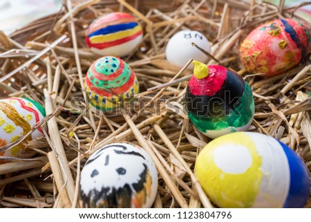 Hand painted Easter eggs in a basket with straw.