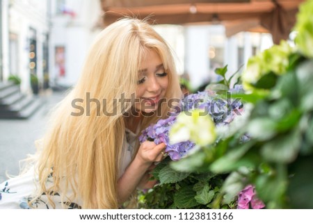 Beautiful woman smelling flowers on the street