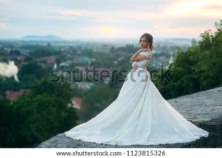 Teenage girl in wedding dress on city. Background town sunset