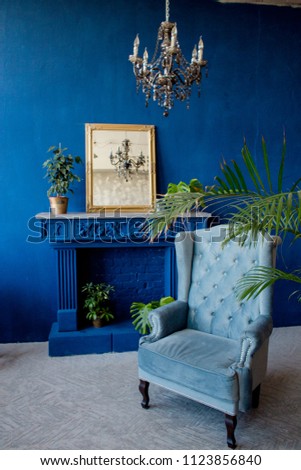 Interior in blue color in classic style next to fireplace