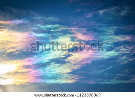 Close-up photo of rainbow-tinted clouds of a 22° solar halo, formed by light reflecting off minuscule ice particles, which are suspended within the clouds on a mid-winter's morning in the Northern 