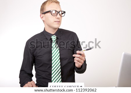 Portrait of a young attractive male receptionist with a sign coffee corner.