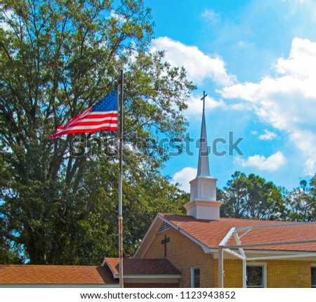 
American flag against the blue sky, green tree and church cross.
Traditional symbol of America in a sunny summer day in the Edom, near Tyler in Texas.  