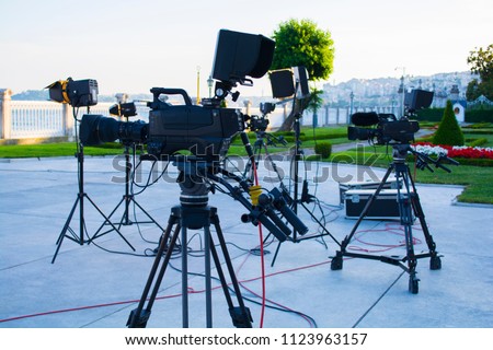 broadcast tv; movie shooting or video production and film, tv crew team with camera, light and audio equipment at outdoor location