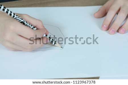 Close-up of the child's hands are drawn with a simple pencil on white paper. Top view.