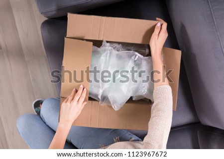 High Angle View Of A Woman's Hand Opening Delivered Parcel