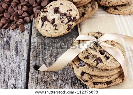 Fresh homemade chocolate chip cookies with chocolate chips and more cookies in the background. Shallow depth of field.