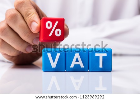 Person's Placing Red Percentage Block Over Vat On White Background Royalty-Free Stock Photo #1123969292