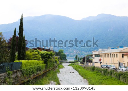 Picturesque italian Mandello landscape with trees, building and mountain in background. Concept of lovely photos of counryside and summer season in village.
