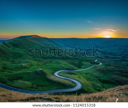 The winding road towards Barber Booth in the Peak District at Sunset viewed from Mam Tor. Royalty-Free Stock Photo #1124015318