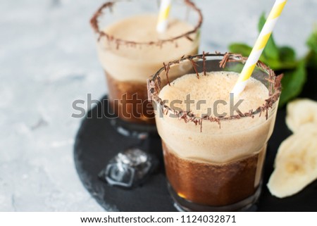 Coffee frappe drink with banana. Cold summer drink on grey background