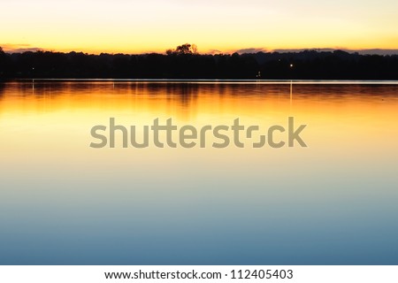 Peaceful scene with distant city lights and soft reflections on calm, still lake at sundown. Taken at Tidal Basin, Washington DC early fall.