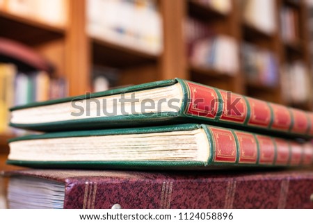 Heap of vintage books closed on library desk with bookshelf out of focus in background