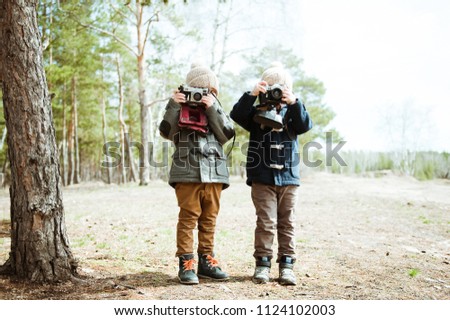 Two preschooler boys take pictures on retro cameras.