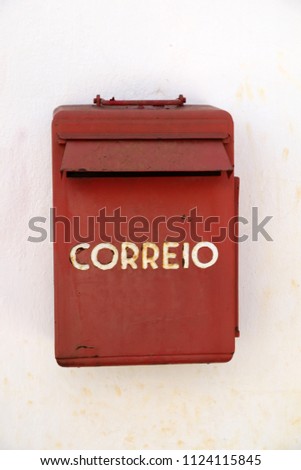 A Portuguese weathered red mail box on a white wall