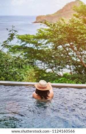 Woman on vacation staying in pool with beautiful view