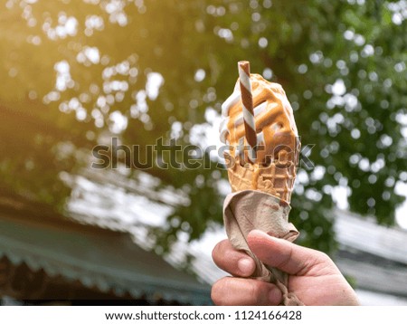 Man holding a melted ice cream waffle cone in hand on outdoor background. Ice cream is popular in summer.