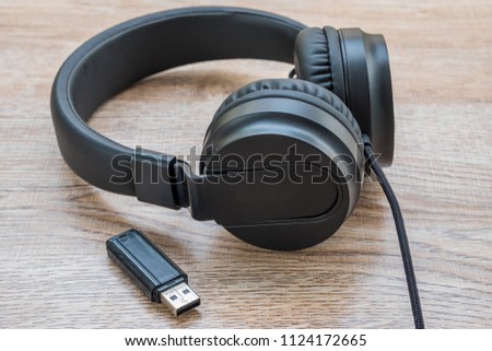 Black headphone and thum drive put on wooden foor.