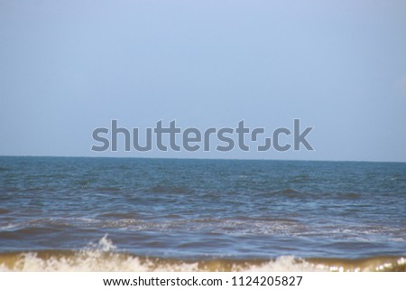 Turquoise ocean sea waves on horizon under clear blue sky.