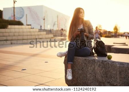 Photographer girl sit on the rock and look ar her camera