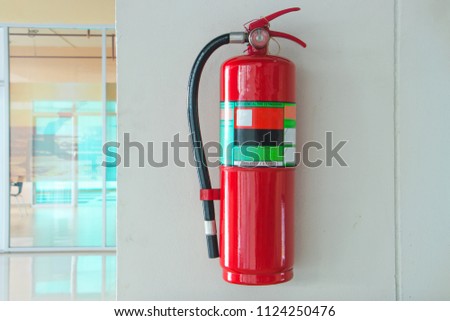 Fire extinguisher on the white cement wall background.