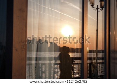 Reflection of the sunset and lanterns in the window of the embankment cafe