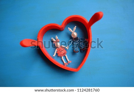 two rabbits beads and red heart blue background