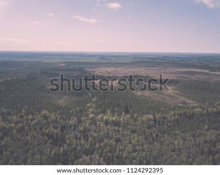 drone image. aerial view of rural area with fields and forests and swamp lake with blue water. latvia - vintage film look