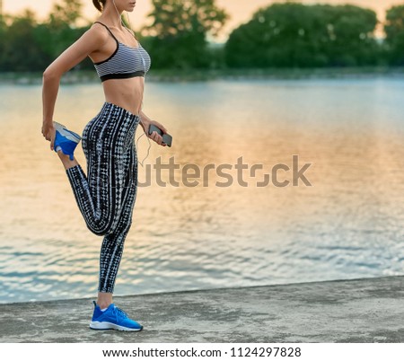Cropped photo of girl making exercises on fresh air. Stretching, yoga, fitness. Model maintaining healthy lifestyle, sporty figure, nice appearance. Lake on background. Evening, beatiful nature.