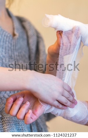 The girl bending her sister's hand. Two, girls, play, doctor. Bandage your arm with a bandage. Hand injury. First aid. vertical photo.