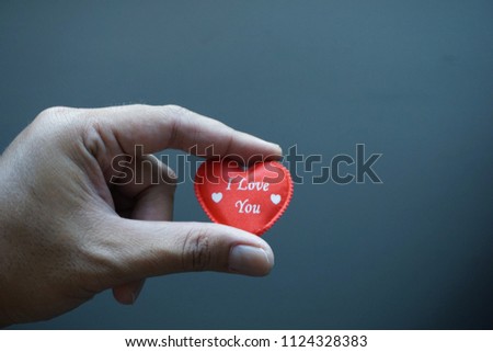 Hand holding the red heart symbol with word I Love You. Dark blur background image.