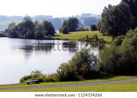Beautiful calm scenery with a lake, trees and meadows in the light of the late afternoon, Allgäu, Bavaria