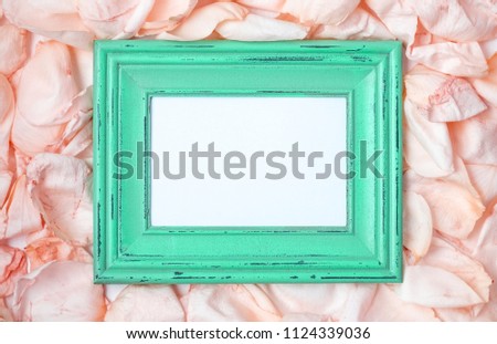 Wooden frame among the petals of roses. Romantic background