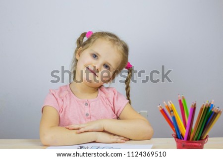 Girl sitting at the table with colored pencils