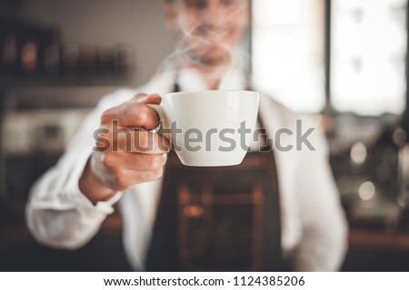 Barista presents cup of hot coffee at cafe, coffee shop business Royalty-Free Stock Photo #1124385206