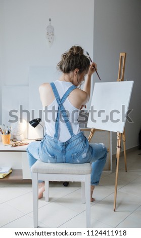 In search of inspiration. Sad Woman painter in front of the canvas and drawing. Artist studio interior. Process in art workshop.