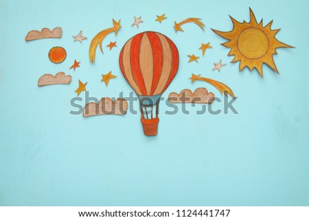 Hot air balloon, space elements shapes cut from paper and painted over wooden blue background