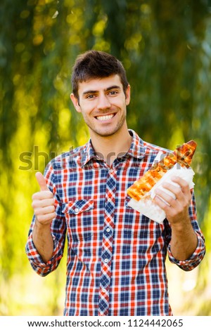 Cheerful young guy is eating pizza on the park