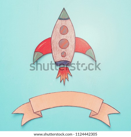 Rocket cut from paper and painted over wooden blue background