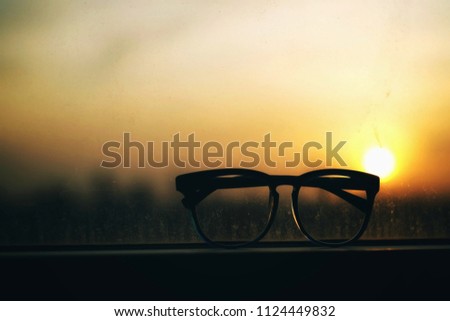 A dark silhouette of glasses with blurred sunset sky background.  