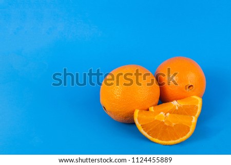 Oranges whole and sliced on solid blue background 