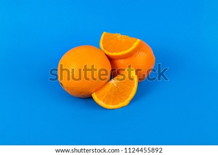 Oranges whole and sliced on solid blue background 