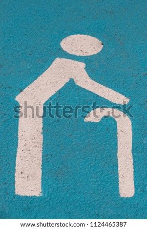 Parking badge for old people painted on blue asphalt.