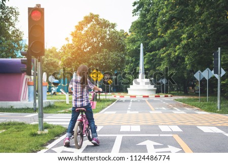 girl is cycling in the park, bicycle stops at traffic lights