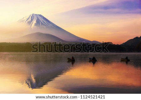 Mt. Fuji or Fujisan with Silhouette three fishermen on boats and mist at Shoji lake during dawn and sunrise in Yamanashi, Japan. Landscape with beautiful skyline reflection on the water. Royalty-Free Stock Photo #1124521421