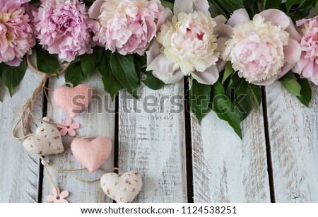 on a light wooden background pink peonies and hearts 
