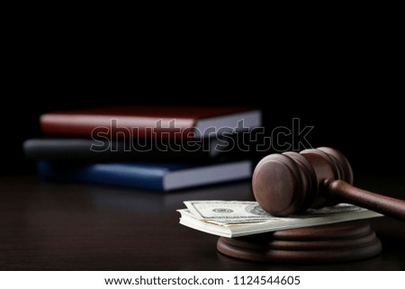 Judge gavel with dollars and books on wooden table