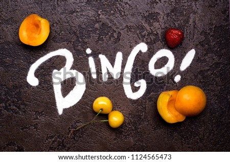 Bingo typography made with powdered sugar, merry berries , apricots and strawberry on a dark background Royalty-Free Stock Photo #1124565473